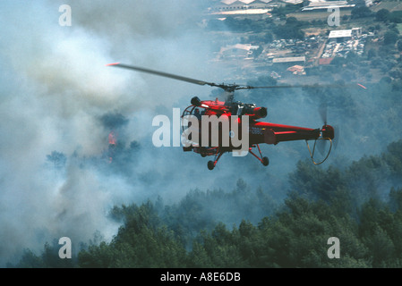 Flying firefighters Alouette III command helicopter hovering in front of a wildfire's smoke cloud, Provence, France, Europe, Stock Photo