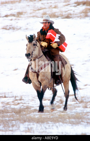 Cowboy on horseback delivering a red Christmas gift box in South Dakota Stock Photo