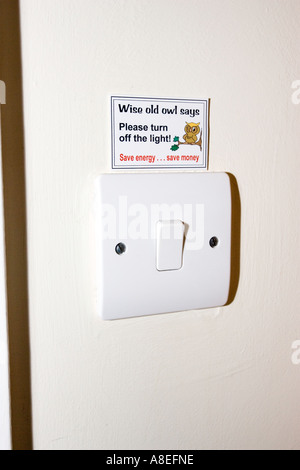 Energy saving sticker above light switch UK Stock Photo