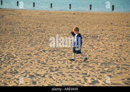 CHICAGO Illinois Young boy walk in sand and carry stick beach along Lake Michigan lakefront Stock Photo