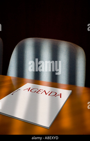 WOODEN BOARDROOM TABLE AND CHAIR WITH SHADOWS OF BLIND ON AGENDA FILE Stock Photo