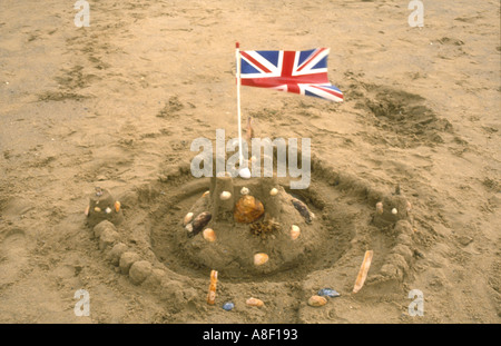A sandcastle with a windswept plastic Union Jack flag on Hunstanton beach, Norfolk, England on a cool summer's day. Stock Photo
