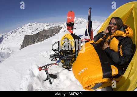 Female mountaineer on cell / sat phone call from camp on mountainside Stock Photo