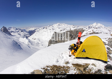 Female mountaineer makes cell or satellite phone call from camp on mountainside. Stock Photo