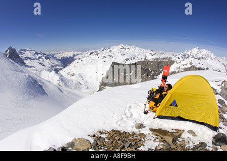 Female mountaineer camped on snowy mountain. Stock Photo
