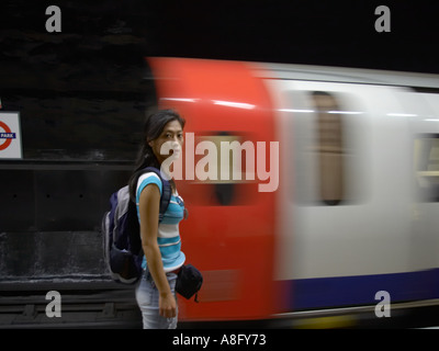 Korean Asian tourist in London Underground  with blurred tube train looking at camera Stock Photo