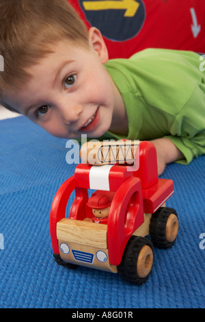 boy playing with wooden toy fire engine toy on floor Stock Photo