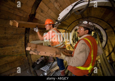 Wearing safety equipment construction workers handle timber Stock Photo