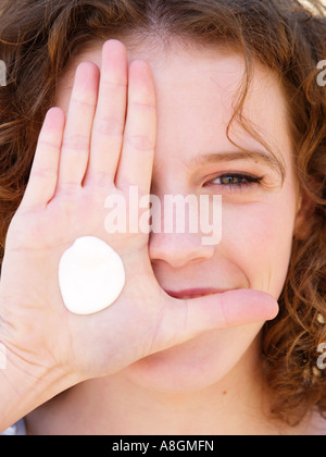 Young woman smiling with blob dab of suncream on her hand Fair skin needs to be protected against uv radiation Stock Photo