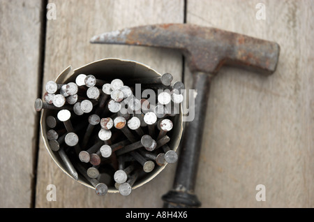 Rusty hammer and nails on wooden board Stock Photo
