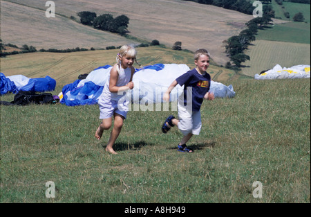 Children boy girl playing skipping to the top of a hill Stock Photo