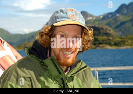 MR young man wearing a cap smiles happy in a boat Lofoten Norway Stock Photo