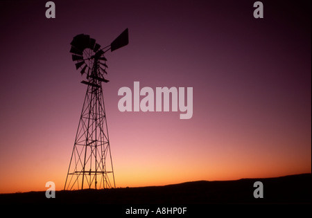 Wind water well silhouetted against the dawn horizon Australian outback Stock Photo