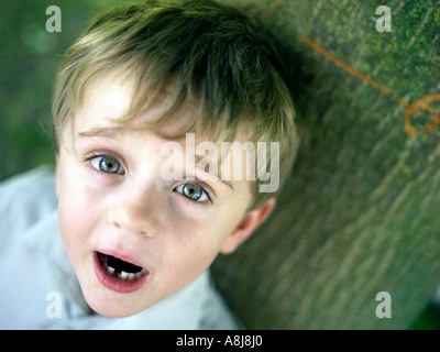 six year old boy with tooth missing leaning on tree with his height and age engraved Stock Photo