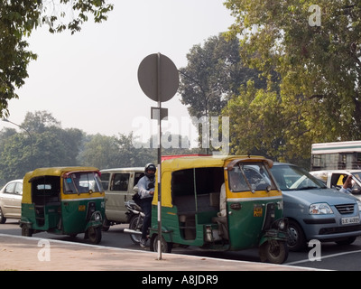 Traffic on busy road with green and yellow auto rickshaw fueled by Compressed Natural Gas CNG. New Delhi India Stock Photo