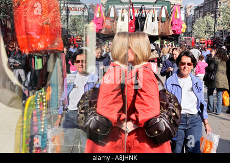a female shopper is reflected by a shop window on Oxford Street, London Stock Photo