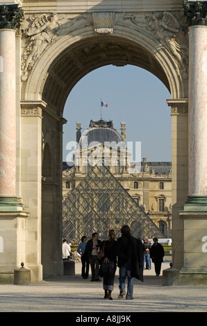 Couple stroll through the Arc de Triomphe du Carrousel with Glass Pyramid and Louvre Museum in the background, Paris, France Stock Photo