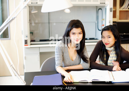 Portrait of two young women studying at a table and grinning Stock Photo