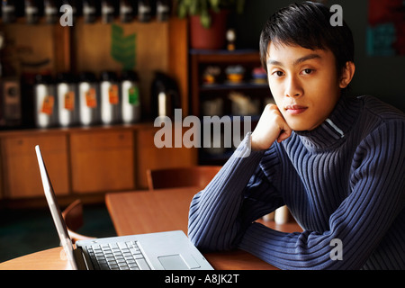 Portrait of a young man sitting in front of a laptop Stock Photo