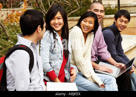 Five young college students sitting together in a college campus and smiling Stock Photo