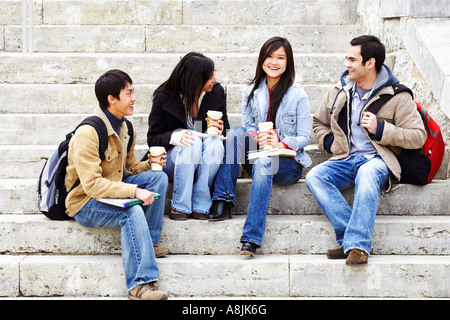 Four college students sitting on steps and smiling Stock Photo