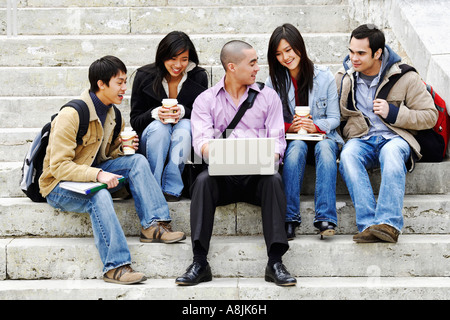 Five young college students sitting on steps and smiling Stock Photo