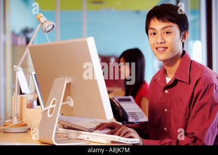Portrait of a businessman sitting in front of a computer in an office and smiling Stock Photo