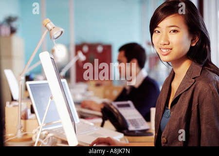 Portrait of a businesswoman sitting in front of a computer in an office and smiling Stock Photo