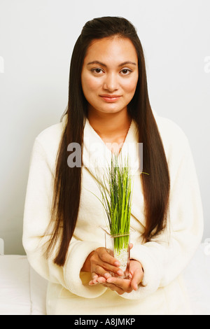 Portrait of a young woman holding wheatgrass and smiling Stock Photo