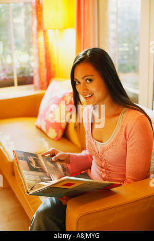 Portrait of a young woman holding a photo album and smiling Stock Photo