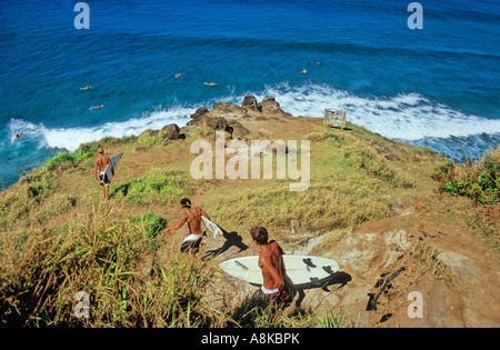 Surfers go down cliff to Honolua Bay surfing spot on Maui Stock Photo