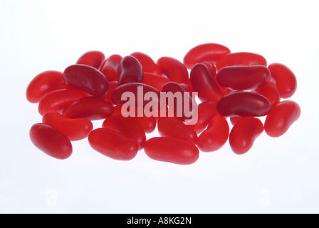 Horizontal close up of lots of identical red jelly beans on a white background. Stock Photo