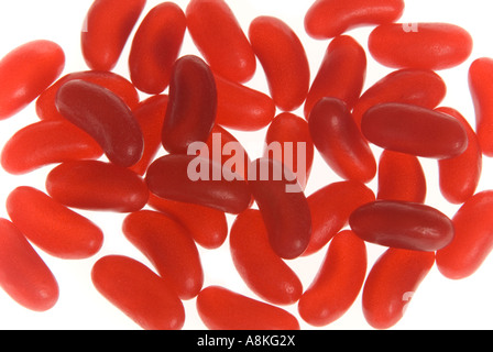 Horizontal elevated close up of lots of identical red jelly beans on a white background. Stock Photo