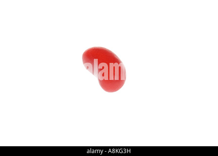 Horizontal close up of one single red jelly bean on a white background. Stock Photo