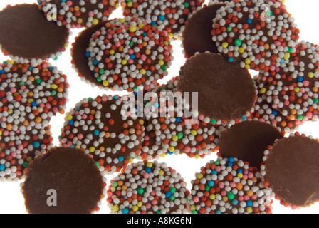 Horizontal elevated close up of a pile of milk chocolate buttons on a white background.