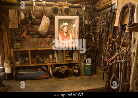 IDAHO INDIAN CREEK GUEST RANCH Cowgirl looking in framed wooden mirror inside western horse tack shack MR Stock Photo