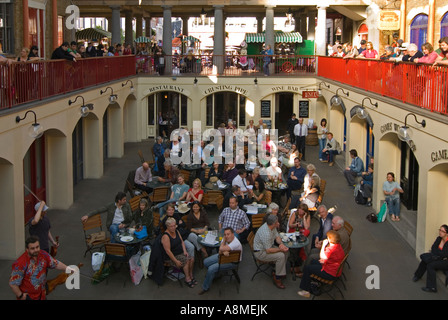 Horizontal close up of people being entertained by street performers inside Covent Garden market on a sunny day Stock Photo