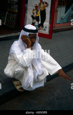 Dubai UAE Man On Mobile Phone In Souk  Squat Sitting Stock Photo