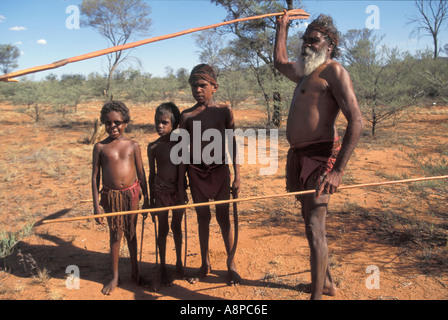 Aboriginal elder teaching young boys to hunt points to animal dropping in Central desert Australia Stock Photo
