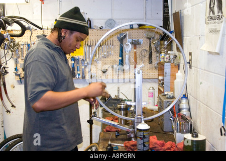 Worker repairing a bicycle wheel. Youth Express Bike Shop St Paul Minnesota USA Stock Photo