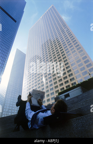 Businessman with cellphone and briefcase resting on downtown Civic Center steps in Los Angeles reading Wall Street Journal Stock Photo