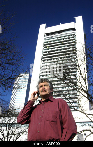 Older man using cell phone in fron of office building Stock Photo
