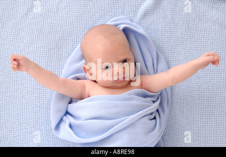Newborn baby with outstretched arms on blue blanket Stock Photo
