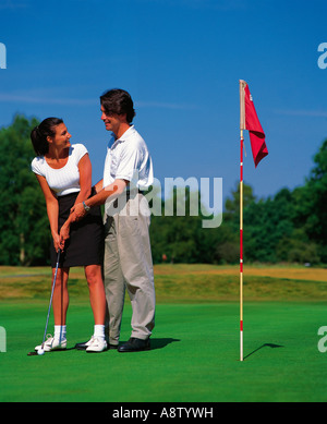 Couple playing golf.  Man instructing woman on putting green. Stock Photo