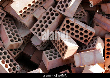 Jumbled messy pile of red bricks with cirlces or holes in them Stock Photo