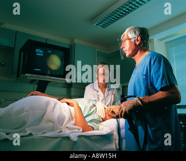 Surgeon and nurse undertaking endoscopy procedure on female patient in hospital. Stock Photo