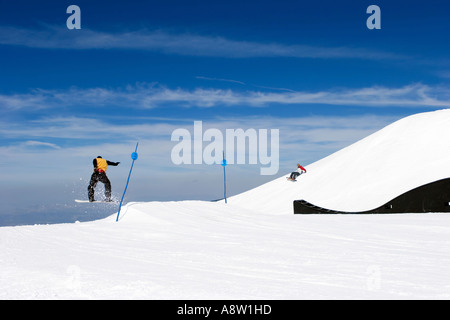 Snowy ski slopes of Pradollano ski resort in the Sierra Nevada mountains in Spain with snowboarder making a jump Stock Photo