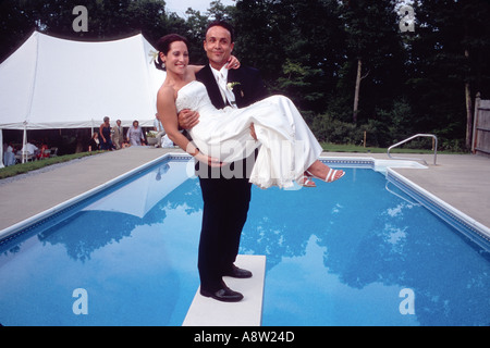 Happy couple bride and groom after wedding ceremony standing on diving board over pool traditional american wedding ceremony Stock Photo