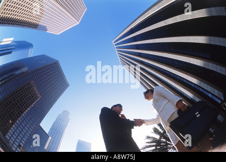 Businessman and woman shaking hands under downtown Los Angeles skyscrapers Stock Photo