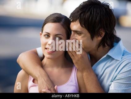 Young man whispering into girlfriend's ear